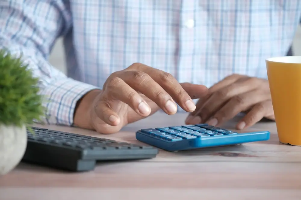 ماشین‌حساب و کیبورد روی میز؛ محاسبه‌ی مالیات شرکتی و ارزش افزوده برای کسب‌وکار