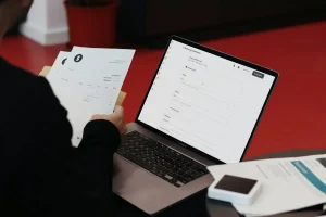 مرور فاکتور کاغذی کنار نرم‌افزار صدور فاکتور روی لپ‌تاپ برای آمادگی فاکتور الکترونیکی امارات