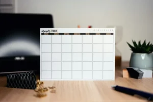 تقویم انطباق شرکت در دبی: تقویم رومیزی سفید روی میز چوبی برای برنامه‌ریزی مهلت‌ها